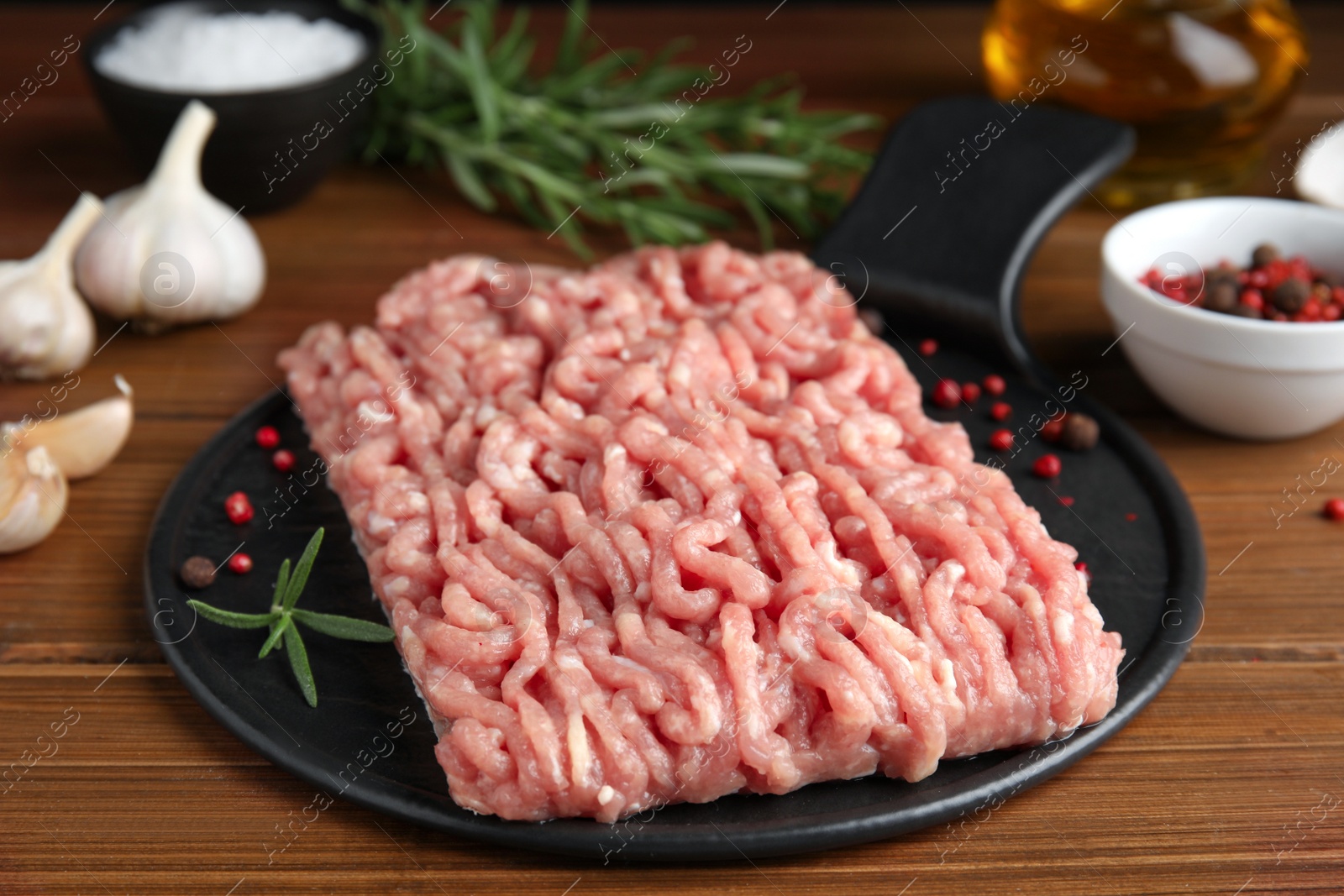Photo of Raw chicken minced meat with spices and rosemary on wooden table, closeup