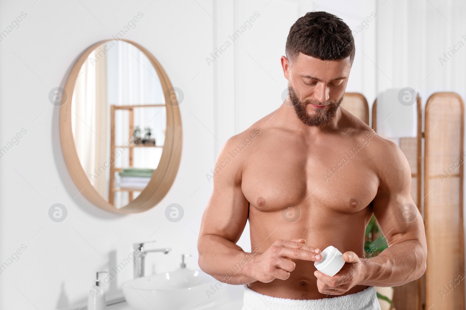 Photo of Handsome man applying body cream in bathroom. Space for text