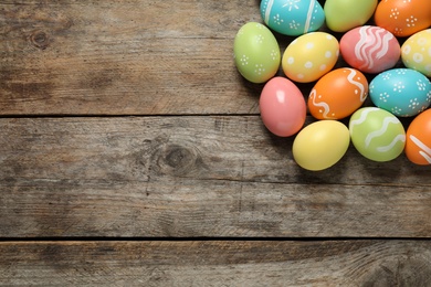 Photo of Many colorful painted Easter eggs on wooden background, top view. Space for text