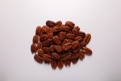 Photo of Pile of delicious fresh pecan nuts on white background, top view