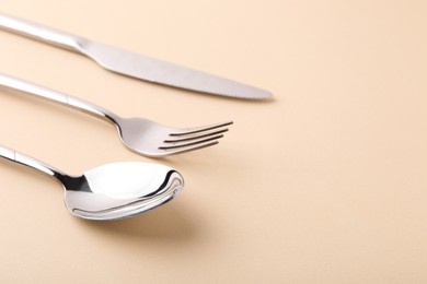 Photo of Stylish silver cutlery set on beige background, closeup. Space for text