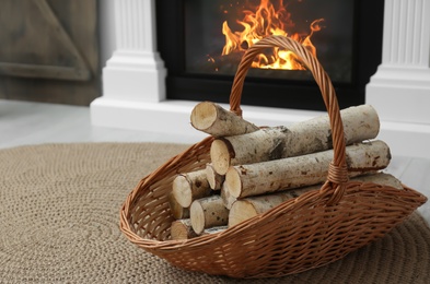 Photo of Firewood in wicker basket near fireplace indoors