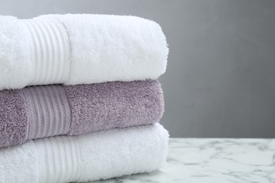 Photo of Stack of folded terry towels on white marble table, closeup. Space for text