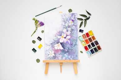 Photo of Flat lay composition with watercolor paints and floral picture on white background
