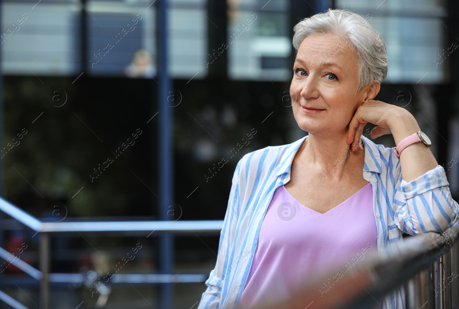 Photo of Happy mature woman near metal handrail on city street, space for text. Smart aging