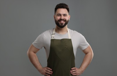 Smiling man in kitchen apron on grey background. Mockup for design