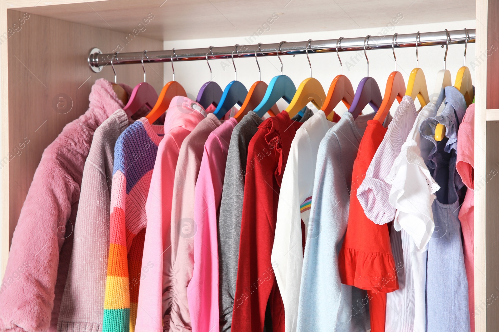 Photo of Wardrobe with stylish girl's clothes hanging on rack