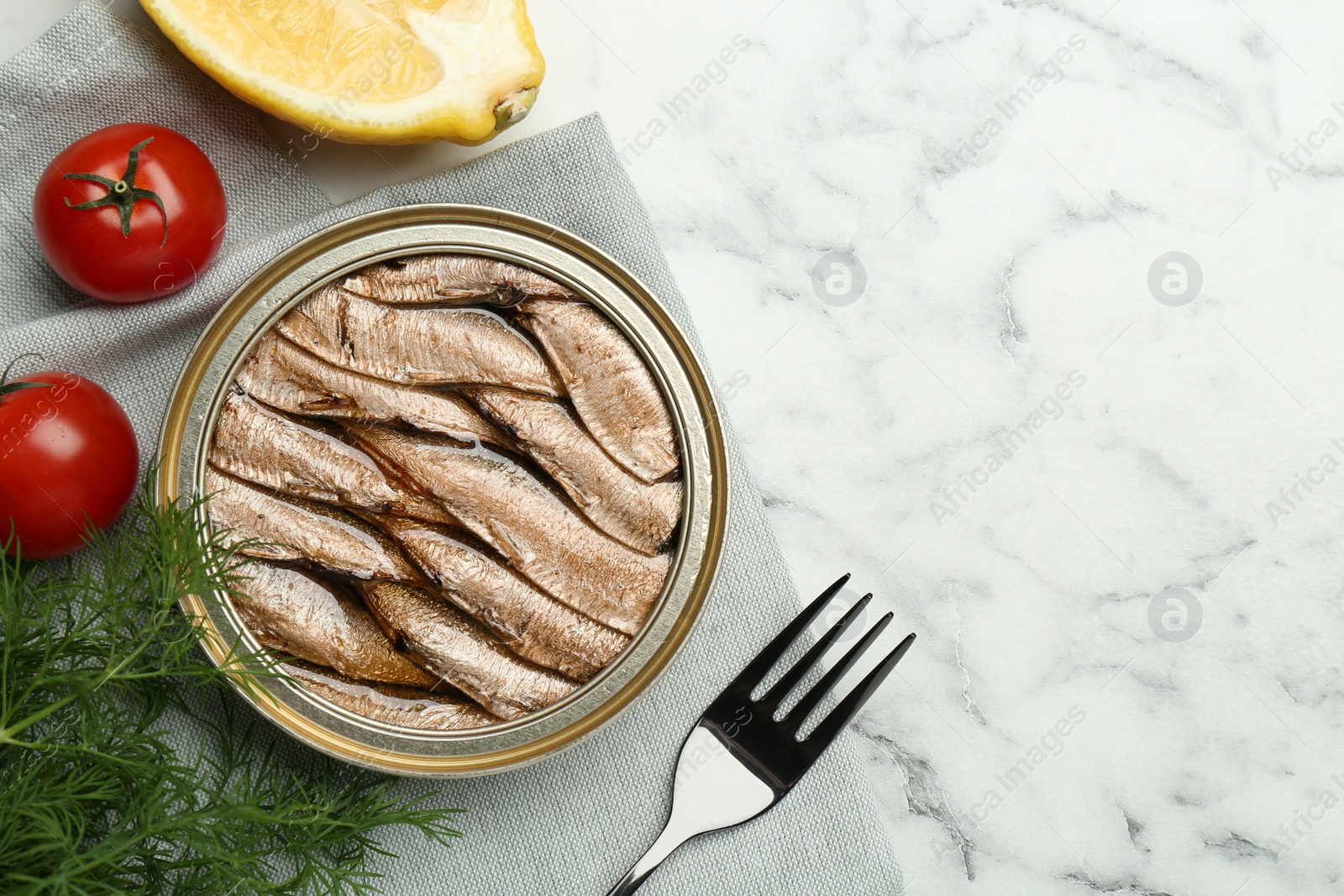 Photo of Tin can with tasty sprats served on white marble table, flat lay. Space for text