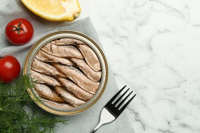 Photo of Tin can with tasty sprats served on white marble table, flat lay. Space for text