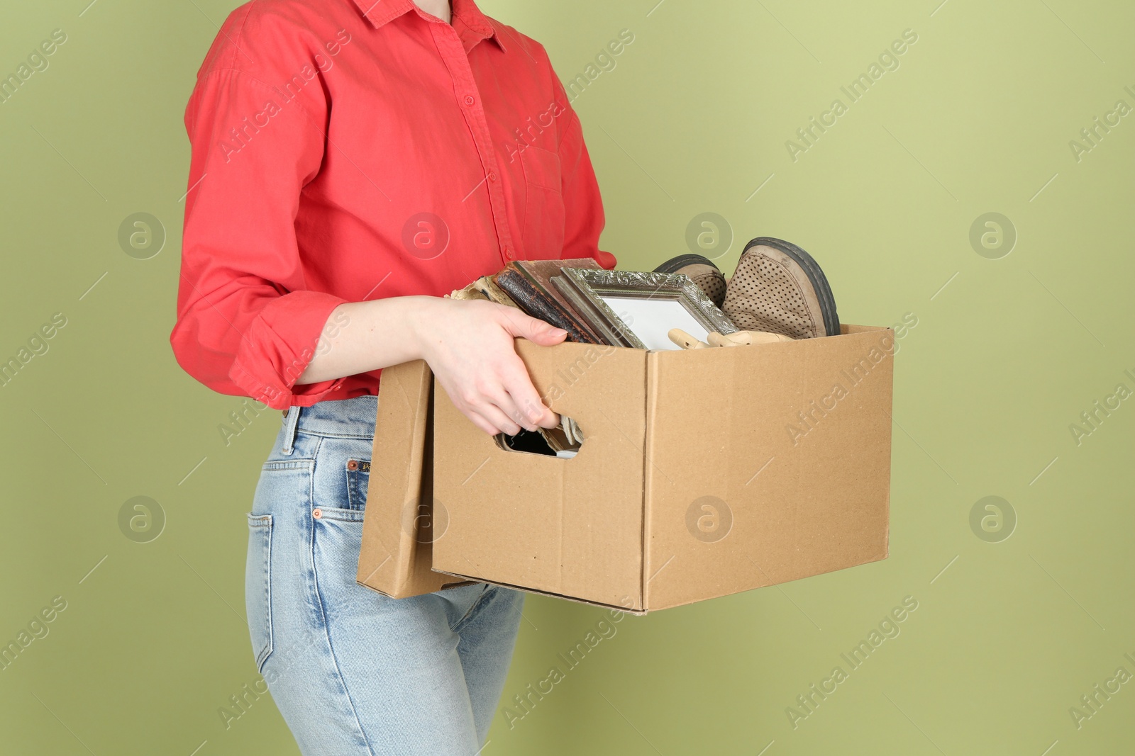 Photo of Woman holding box of unwanted stuff on green background, closeup