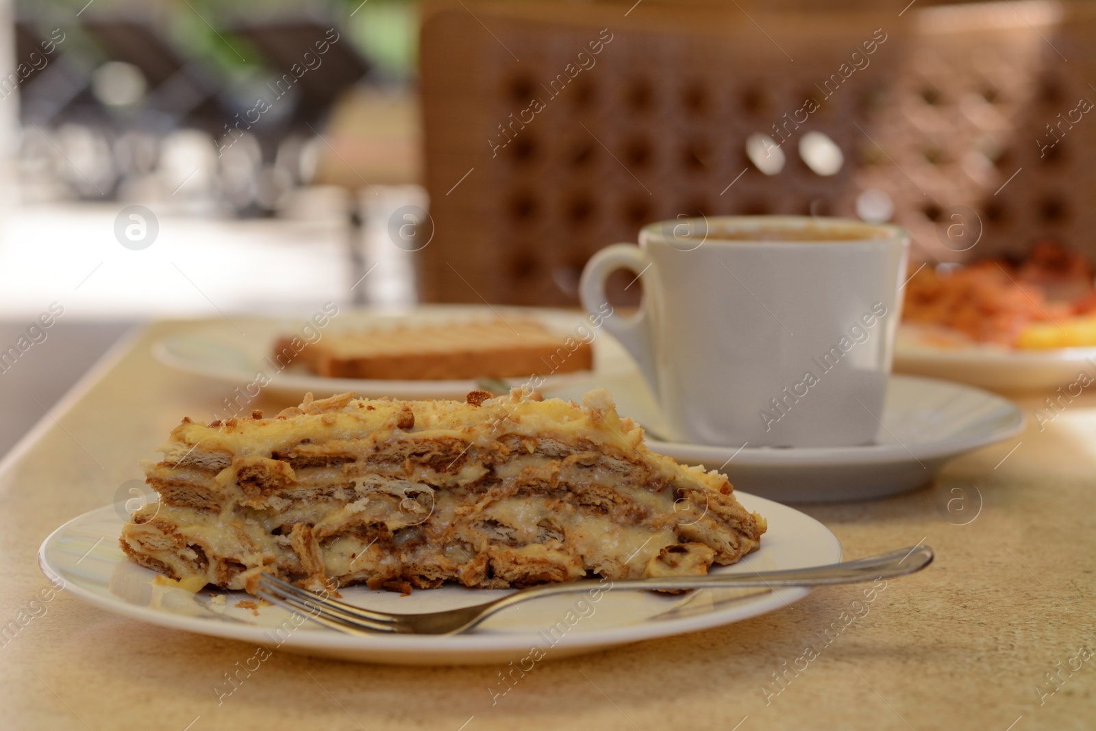 Photo of Piece of delicious cake and coffee on beige table in cafe, closeup