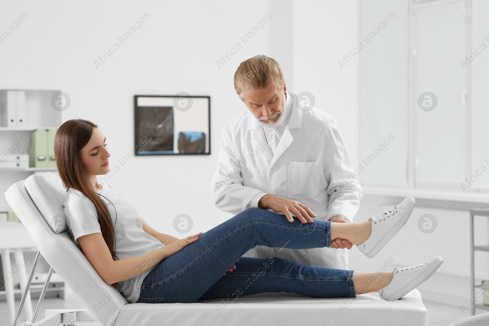 Photo of Orthopedist examining patient with injured knee in clinic