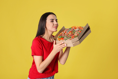 Photo of Beautiful woman with tasty pizza on yellow background