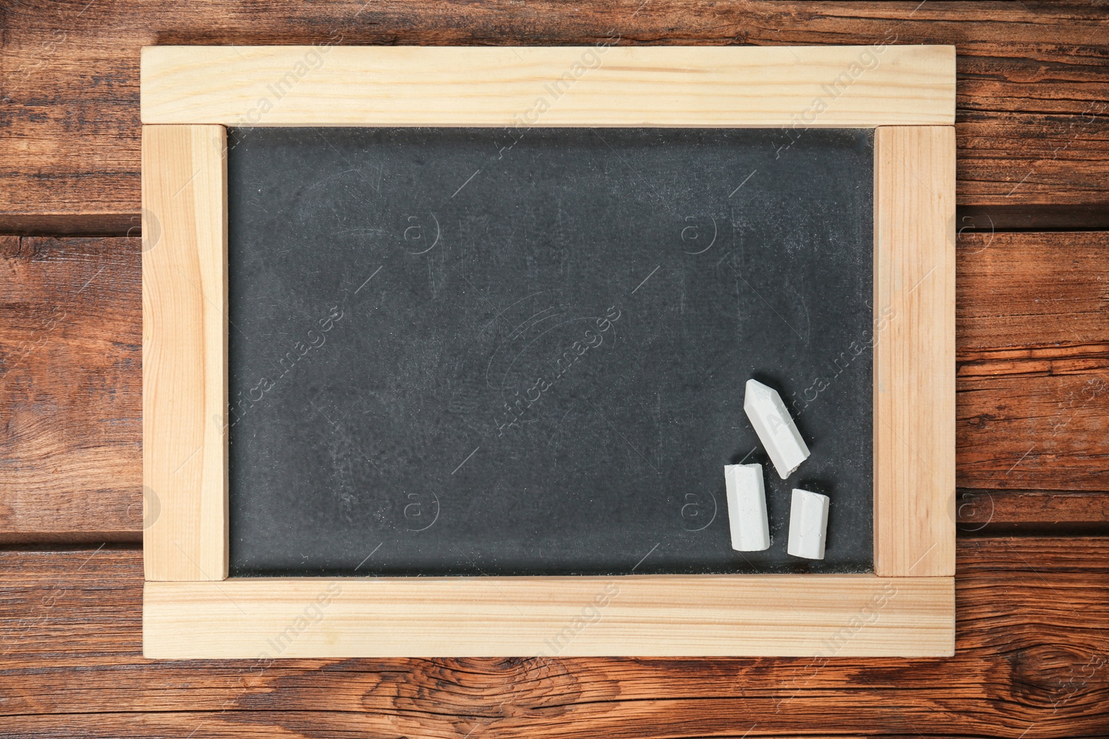Photo of Empty clean blackboard with chalk on wooden background
