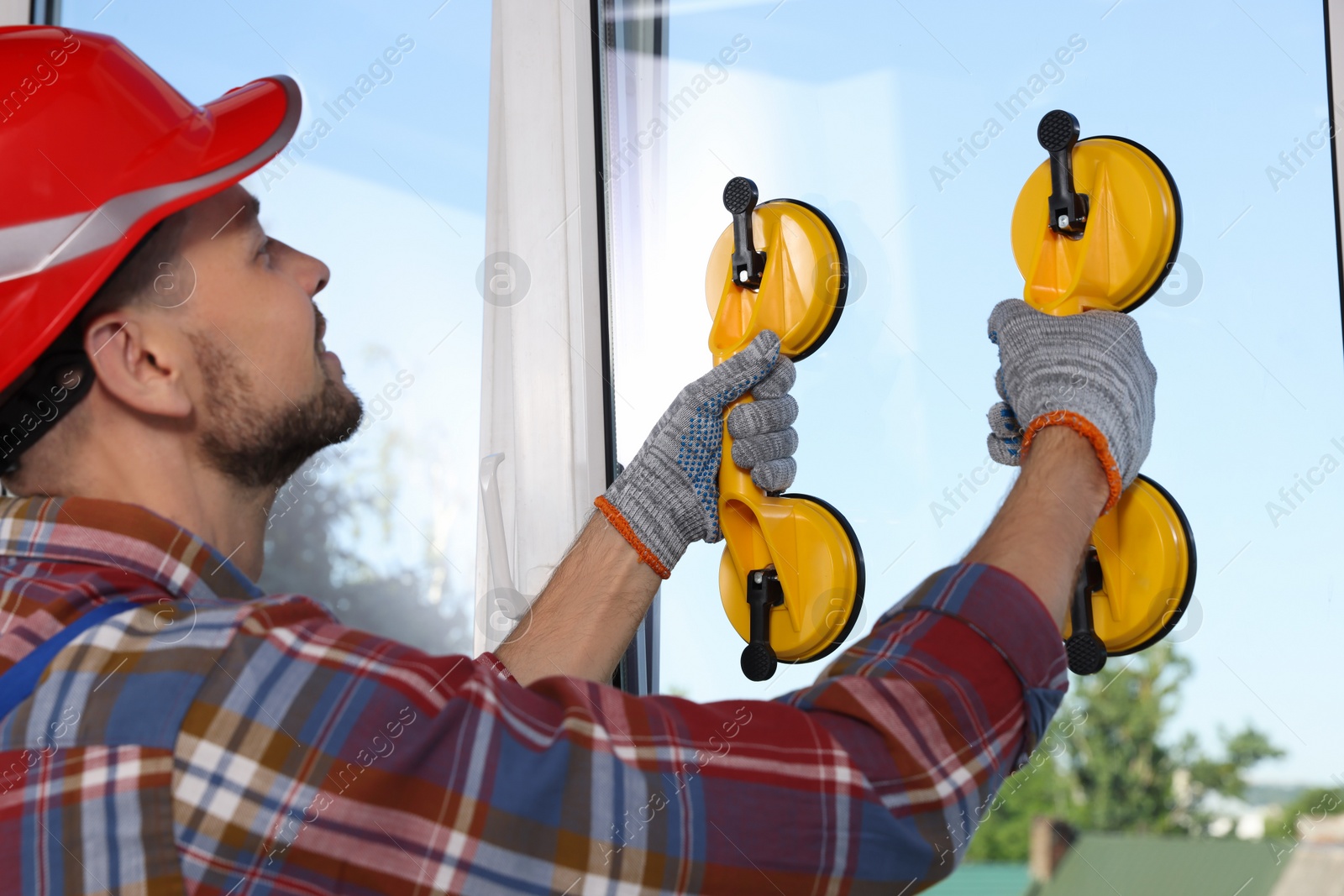 Photo of Worker using suction lifters during plastic window installation indoors
