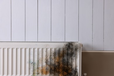 Image of Modern panel radiator affected by rust on white wooden wall