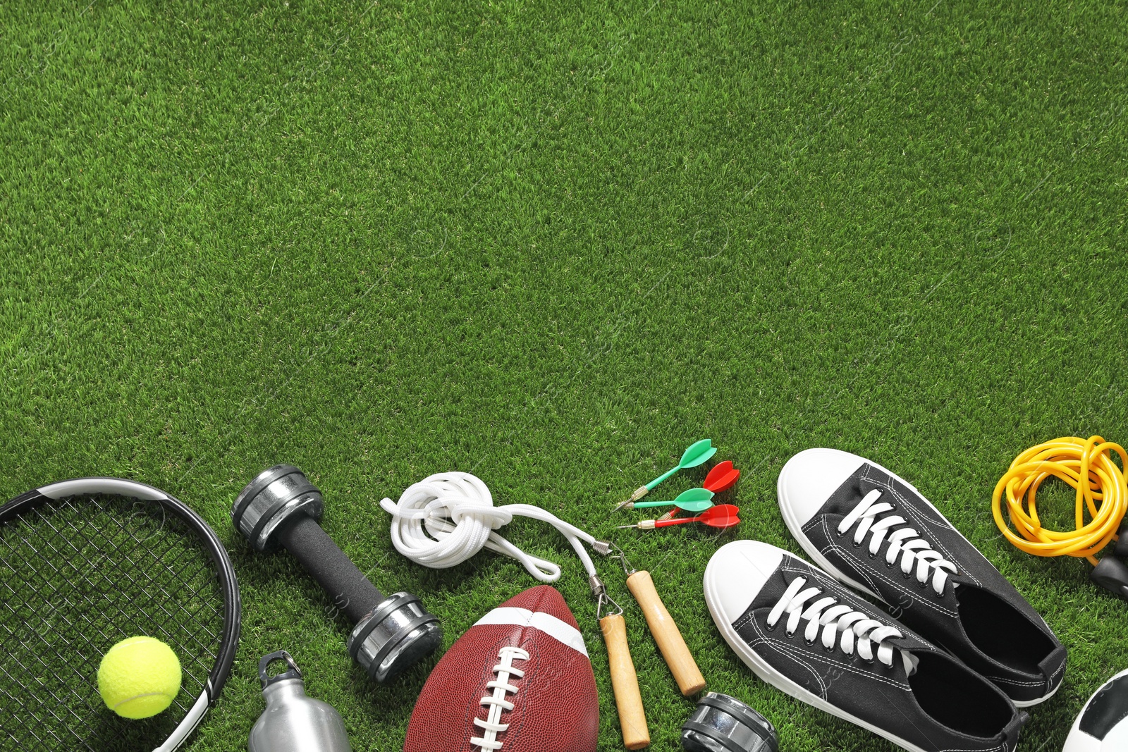 Photo of Different sports equipment on green grass, flat lay. Space for text