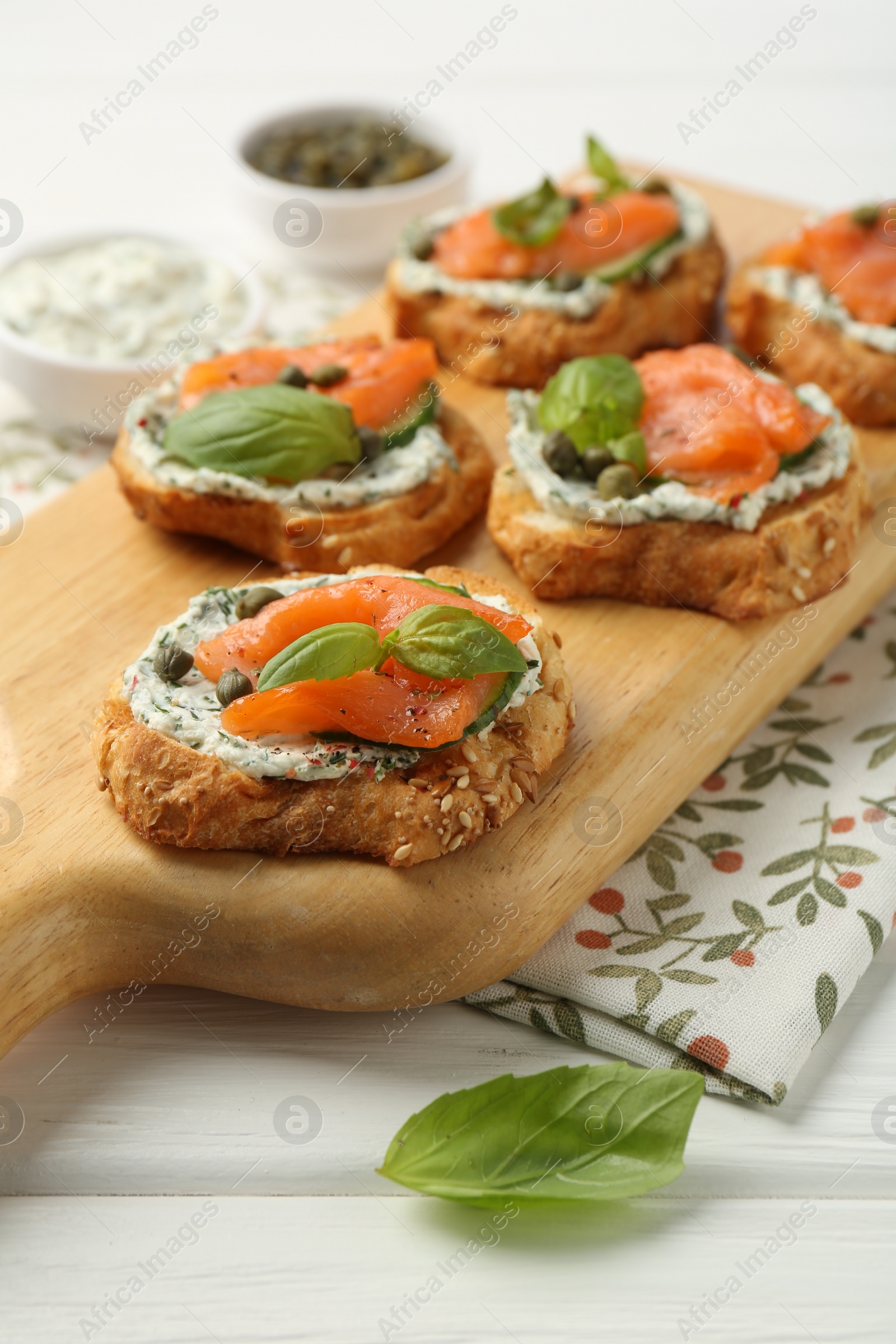 Photo of Tasty canapes with salmon, capers and sauce on white wooden table