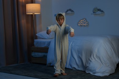 Boy in pajamas sleepwalking indoors at night