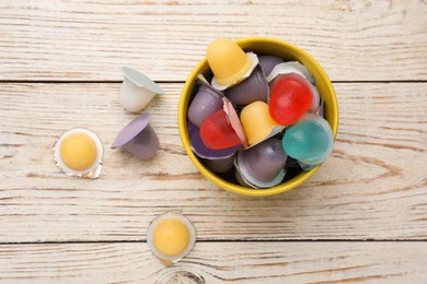 Photo of Bowl with tasty bright jelly cups on white wooden table, flat lay