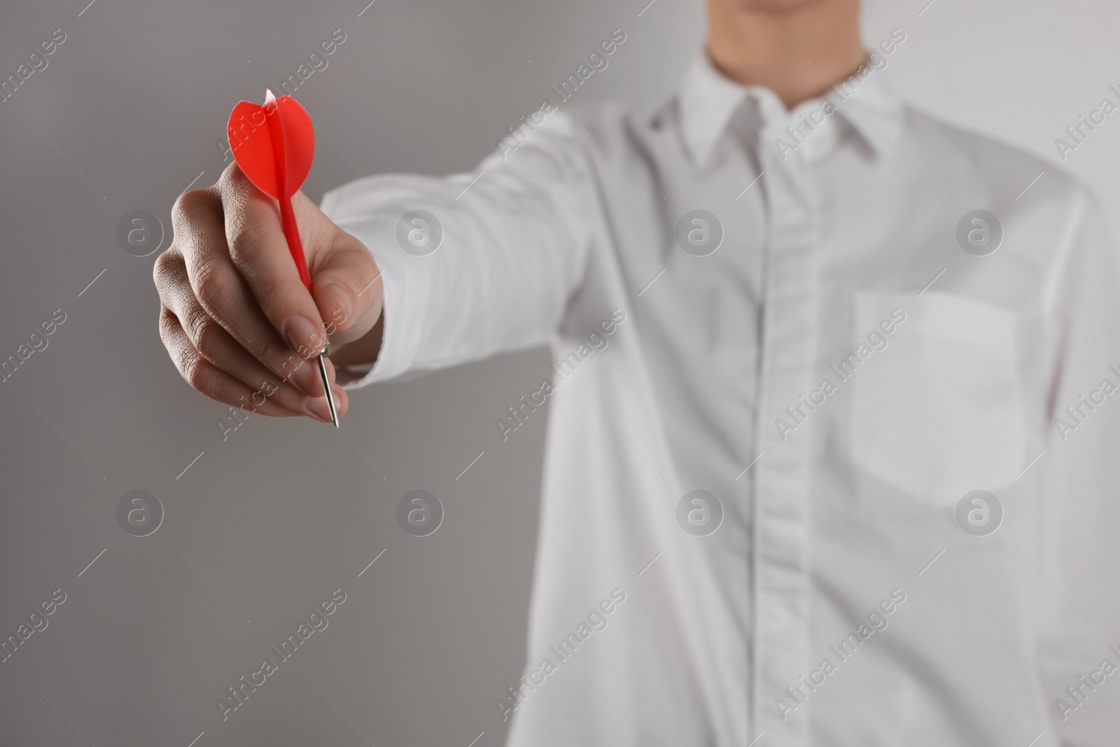 Photo of Businesswoman holding red dart on grey background, closeup