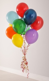 Photo of Bunch of bright balloons against light wall. Celebration time