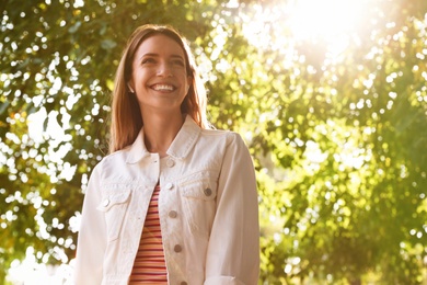 Photo of Young woman with wireless headphones listening to music in park. Space for text