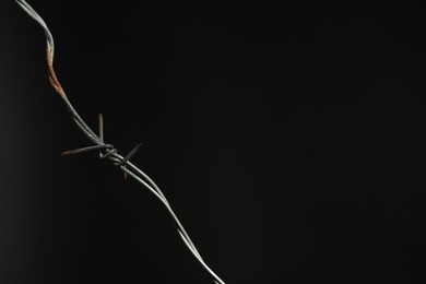 Photo of Metal barbed wire on black background. Space for text