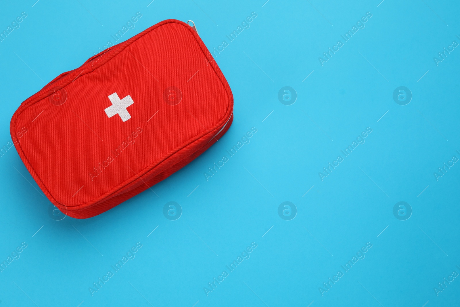 Photo of First aid kit bag on light blue background, top view. Space for text