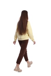 Photo of Young woman in casual outfit walking on white background, back view