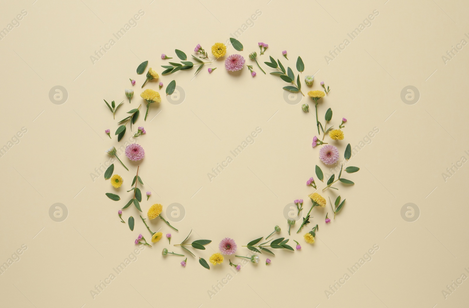 Photo of Wreath made of beautiful flowers and green leaves on beige background, flat lay. Space for text