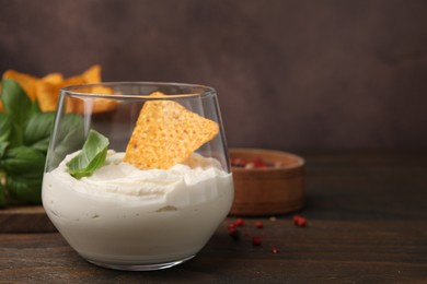 Photo of Delicious tofu sauce served with nachos chip on wooden table, closeup. Space for text