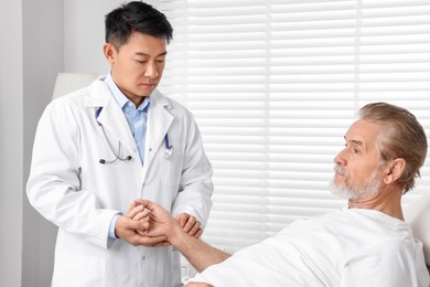 Photo of Doctor checking senior man`s pulse in hospital
