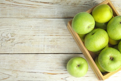 Flat lay composition of fresh ripe green apples on wooden table, space for text