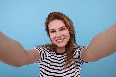 Photo of Beautiful woman taking selfie on light blue background