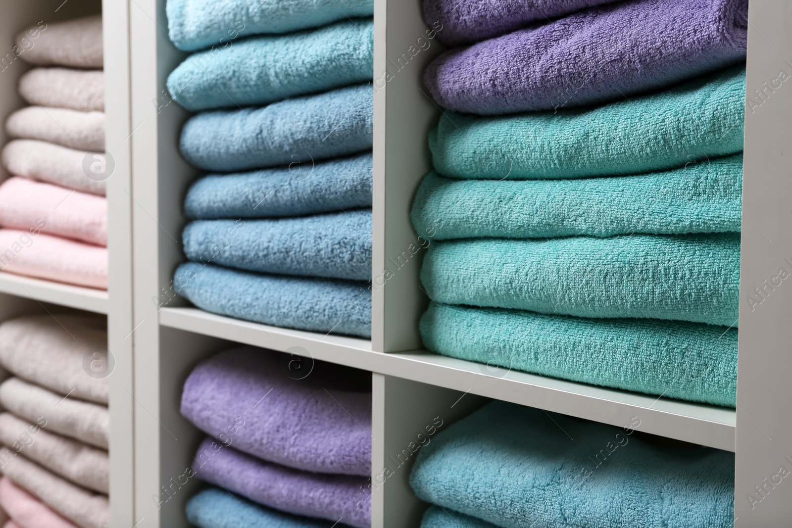 Photo of Colorful towels on shelves, closeup. Bathroom supplies