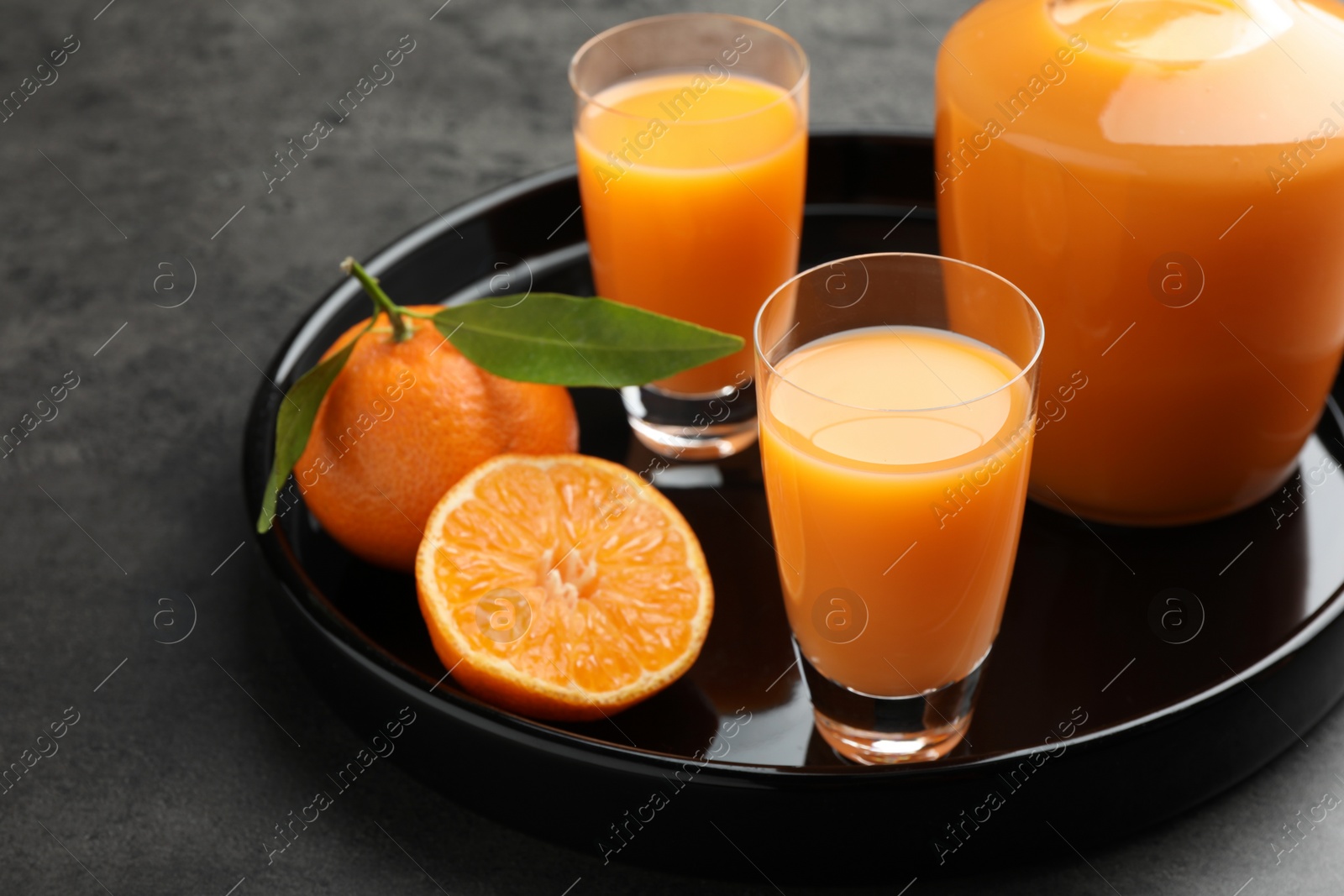 Photo of Delicious tangerine liqueur and fresh fruits on grey table