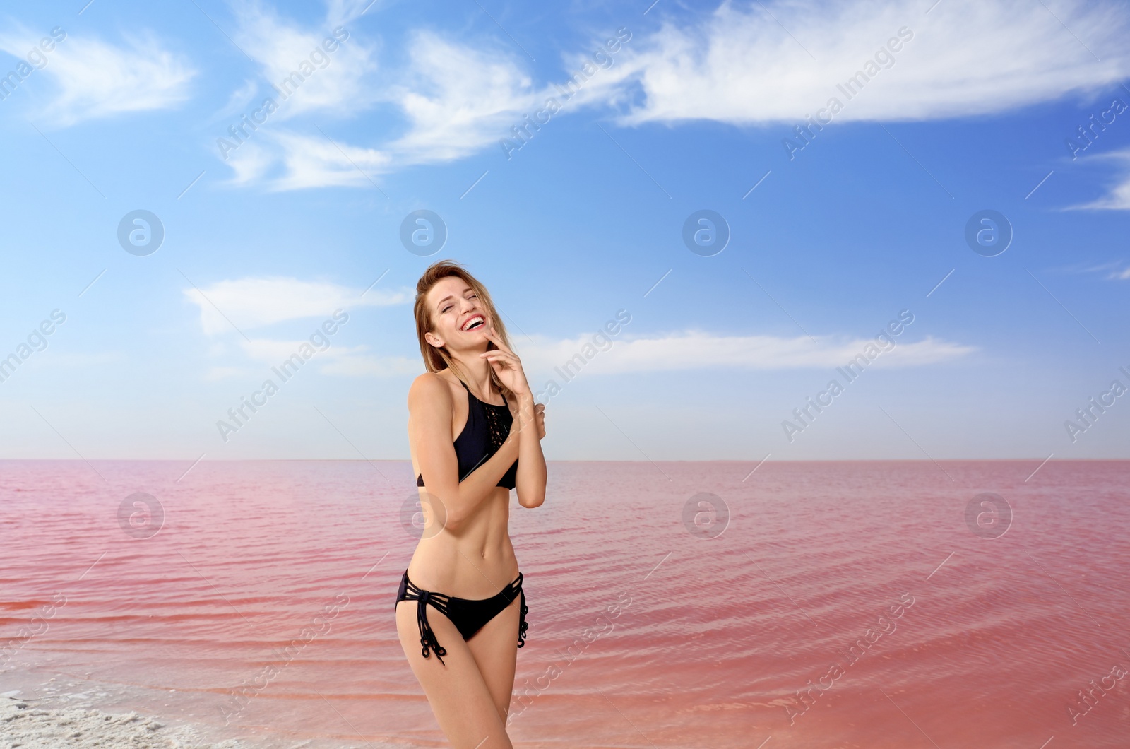 Photo of Beautiful woman in swimsuit posing near pink lake on sunny day