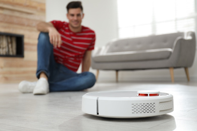Photo of Man using robotic vacuum cleaner at home