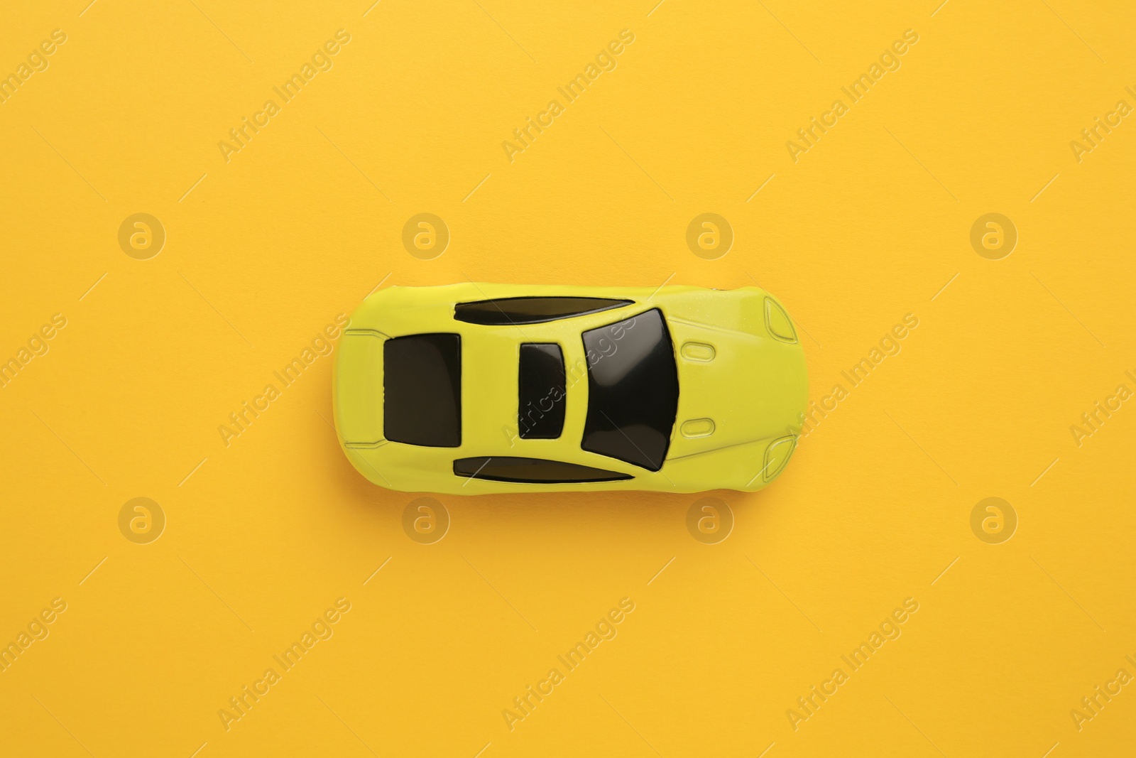 Photo of One bright car on yellow background, top view. Children`s toy