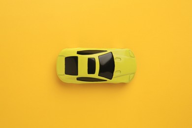 Photo of One bright car on yellow background, top view. Children`s toy