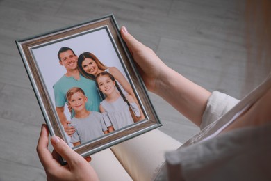 Photo of Woman holding framed family photo indoors, closeup