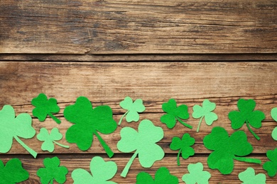 Decorative clover leaves on wooden background, flat lay with space for text. St. Patrick's Day celebration