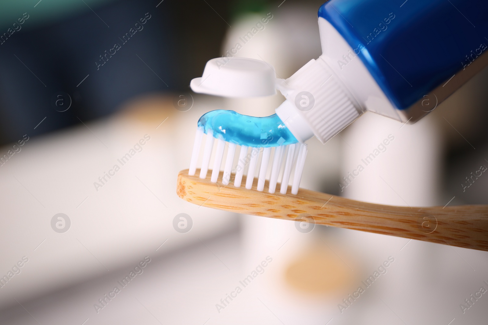 Photo of Applying toothpaste on brush against blurred background, closeup