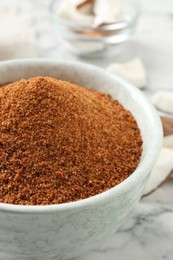 Natural coconut sugar in ceramic bowl on white marble table, closeup