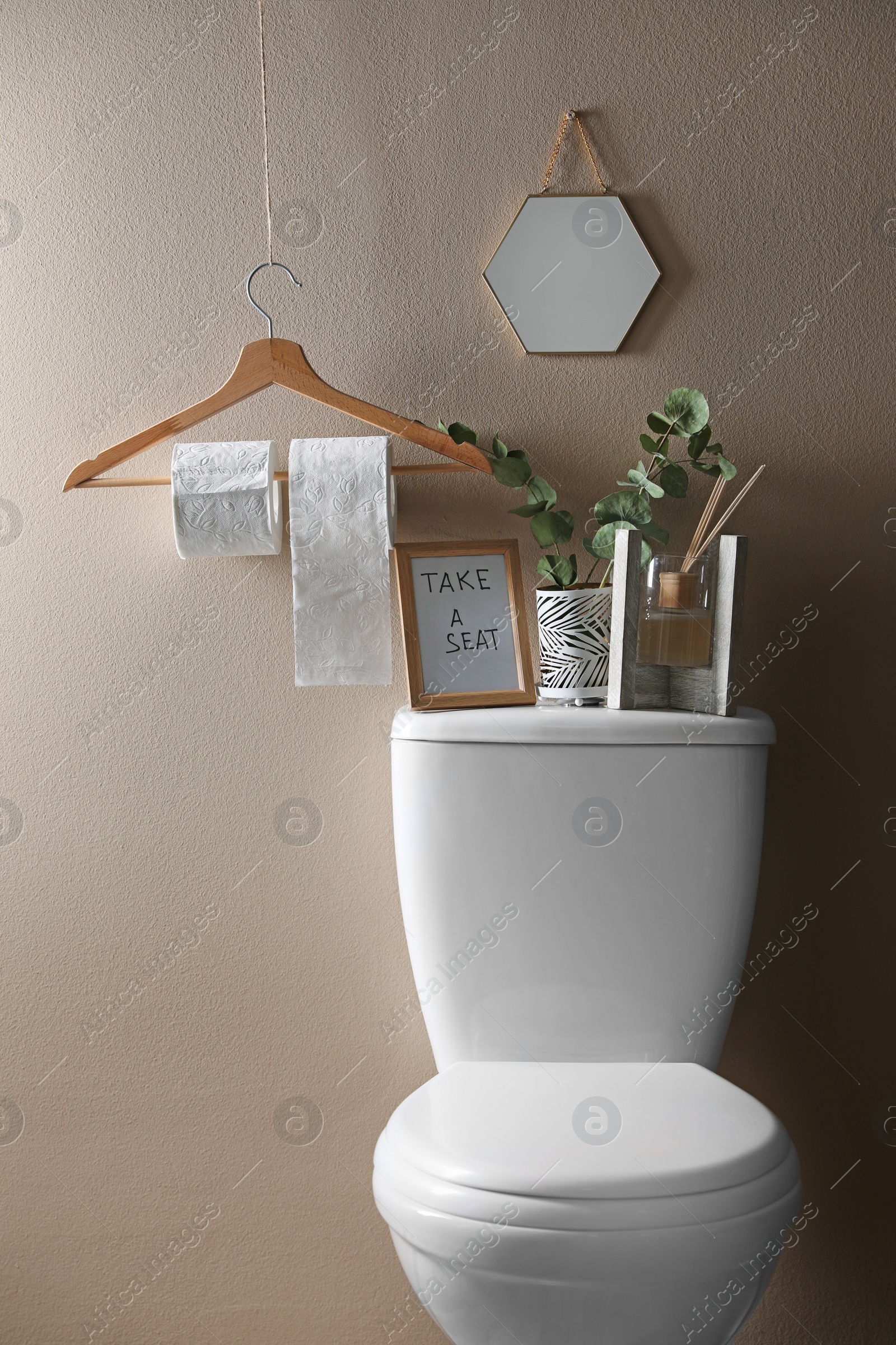 Photo of Decor elements, necessities and toilet bowl near beige wall. Bathroom interior