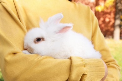 Photo of Woman with fluffy white rabbit outdoors, closeup. Cute pet