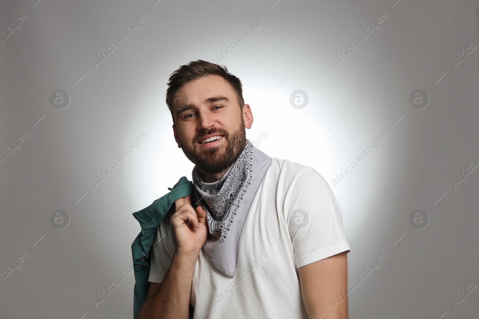 Photo of Fashionable young man in stylish outfit with bandana on grey background