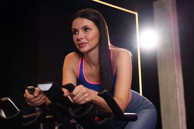 Photo of Young woman training on exercise bike in fitness club