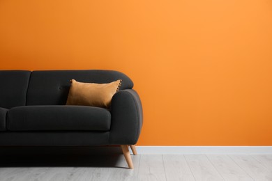 Stylish room with cosy sofa near orange wall, space for text. Interior design